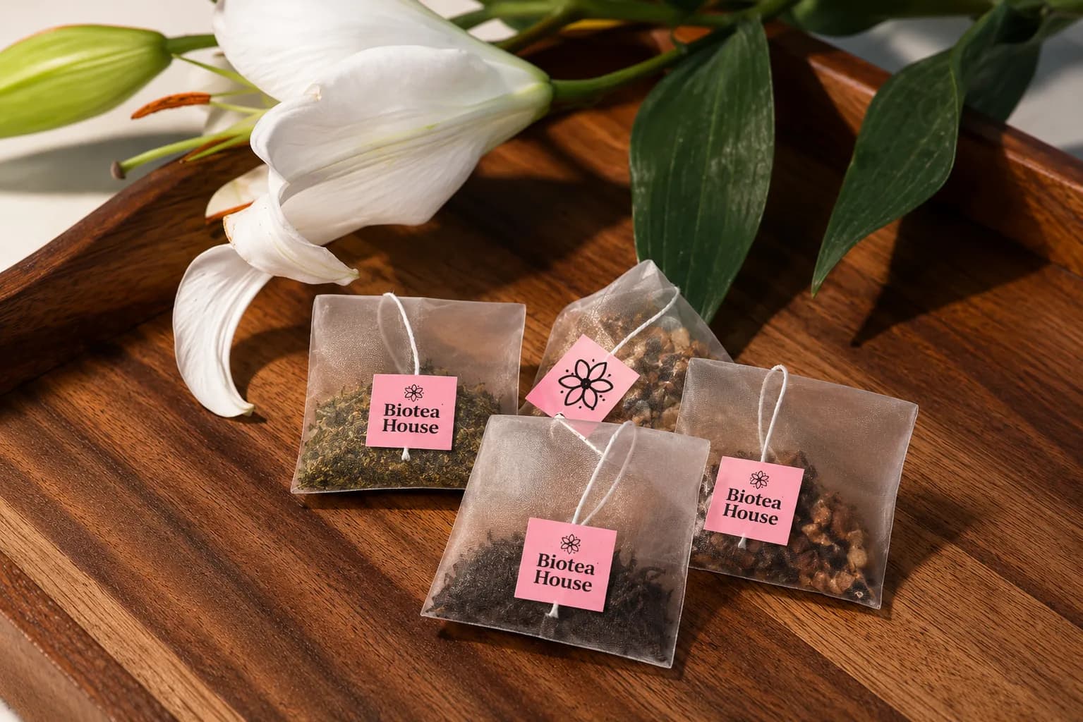Varias bolsitas piramidales de Biotea House con etiquetas rosadas sobre una bandeja de madera.